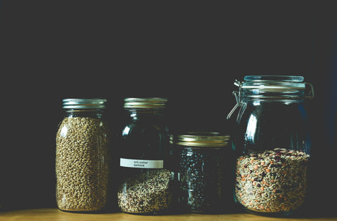 Four glass jars with different contents on a dark background