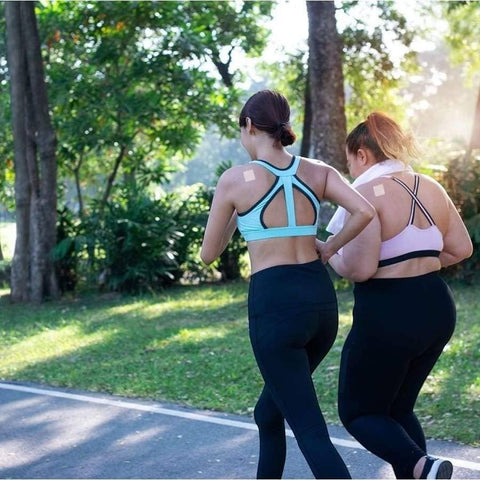 Two women jogging in a park wearing Eden’s Market PatchAid sleep support patches on their shoulders
